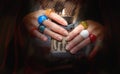 WomanÃ¢â¬â¢s hands with many colorful glass rings holding candlelight with burning candle